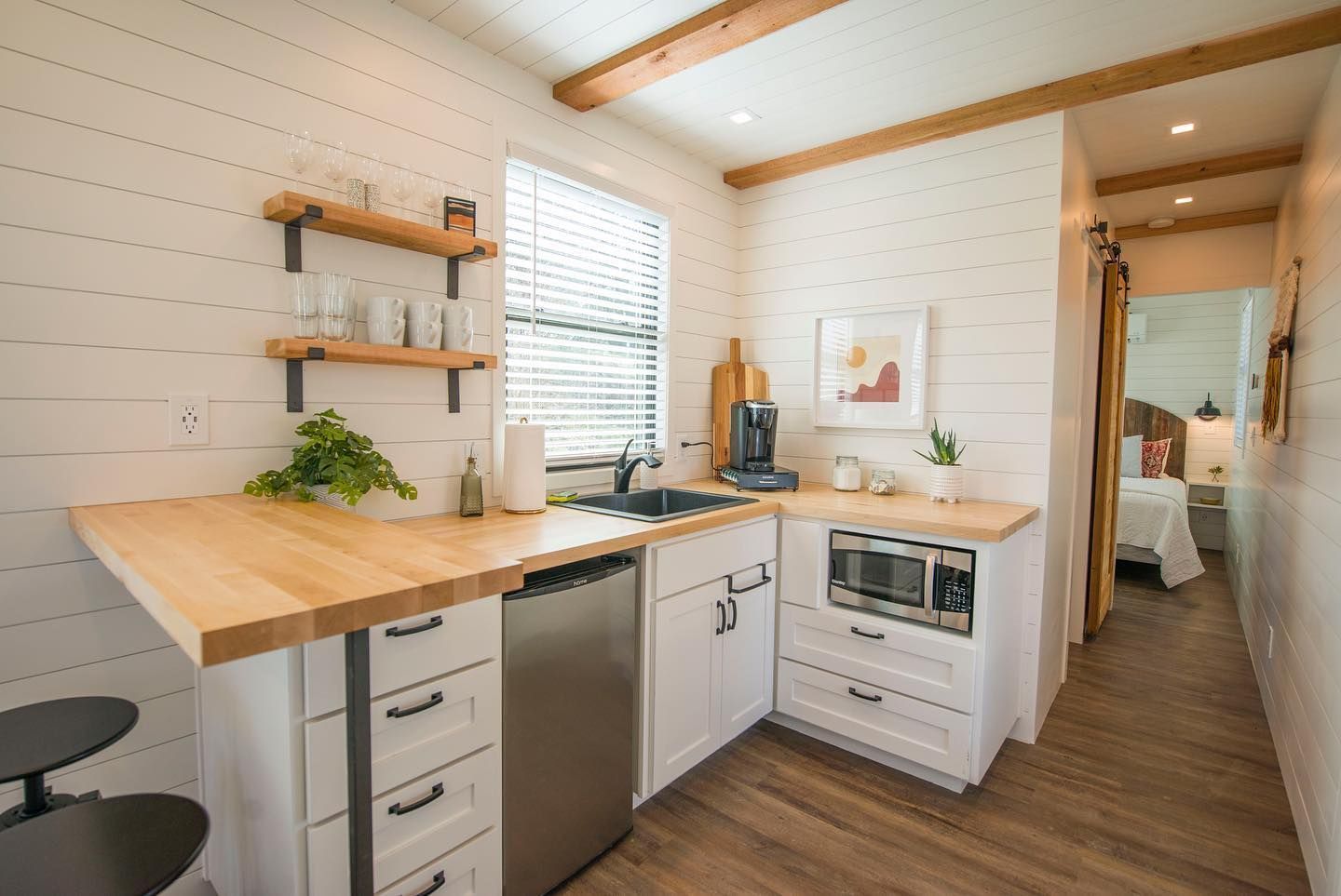A small kitchen with a wooden counter top, stainless steel appliance, and white cabinets.