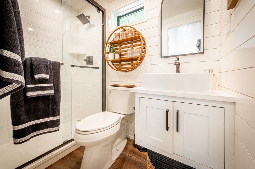 A bathroom with a toilet , sink and shower.