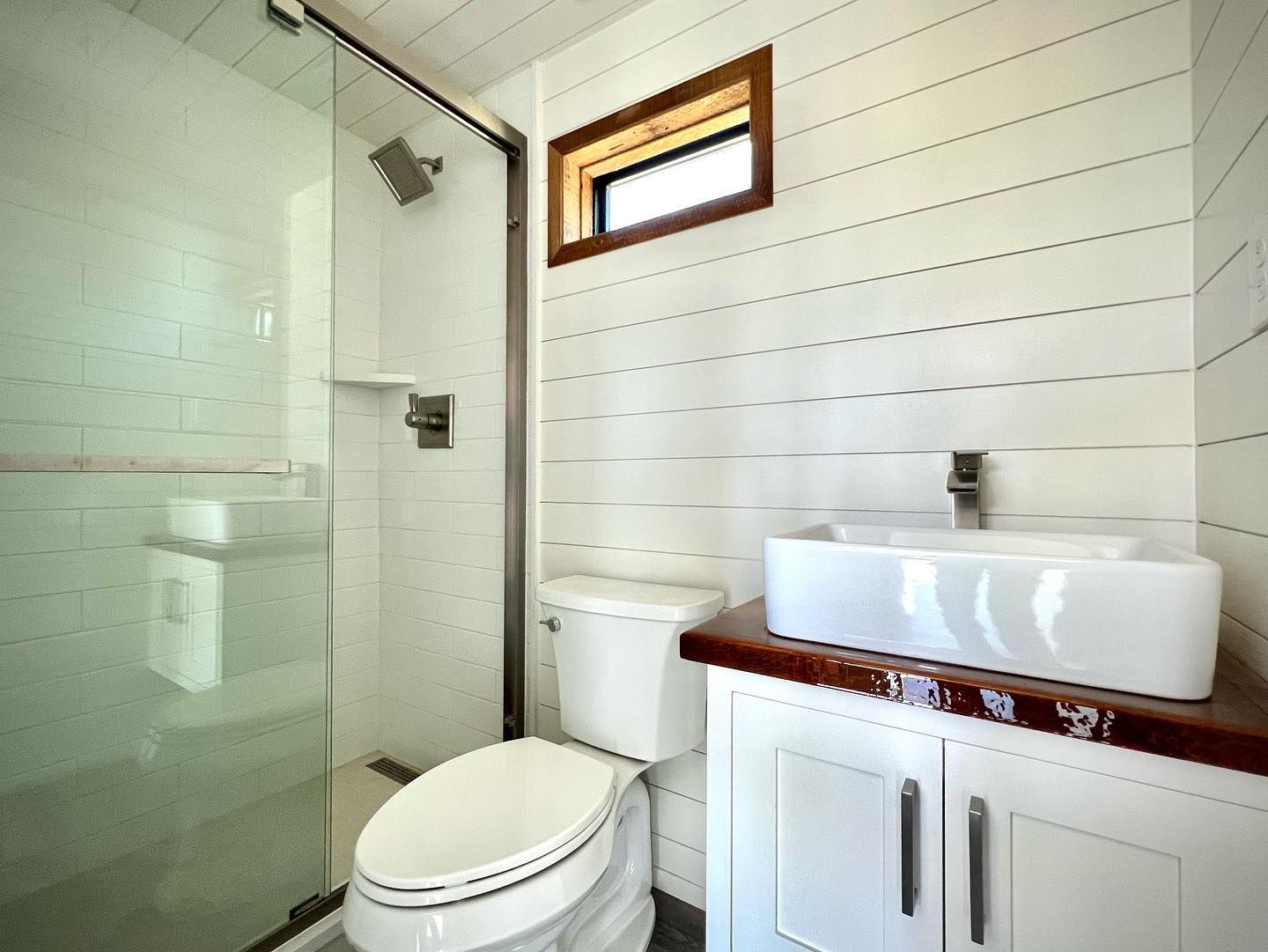 A bathroom with a toilet , sink and shower.