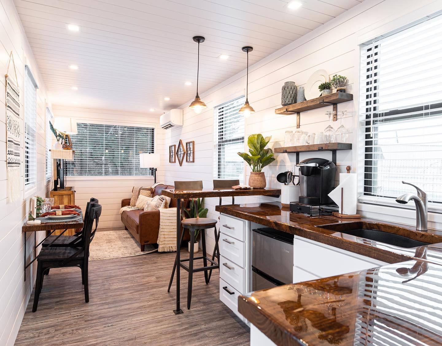 A kitchen with a sink, dishwasher, stove, table and chairs.