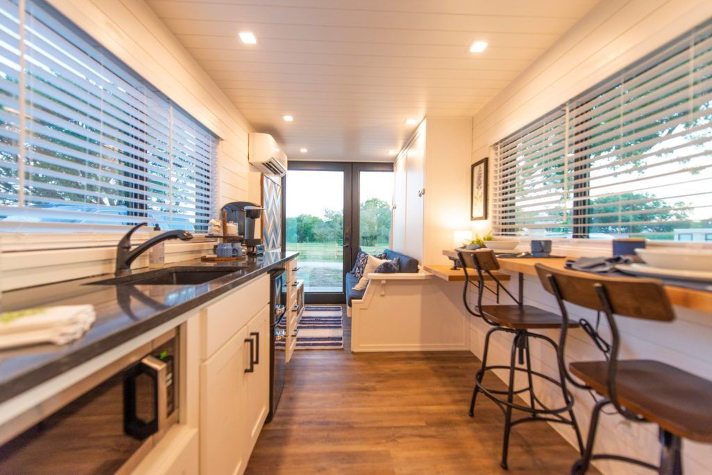 A kitchen with a sink , table and chairs in a tiny house.