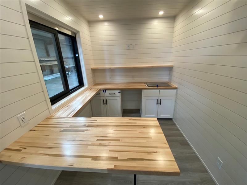 a kitchen with a wooden table, cabinets, and a window