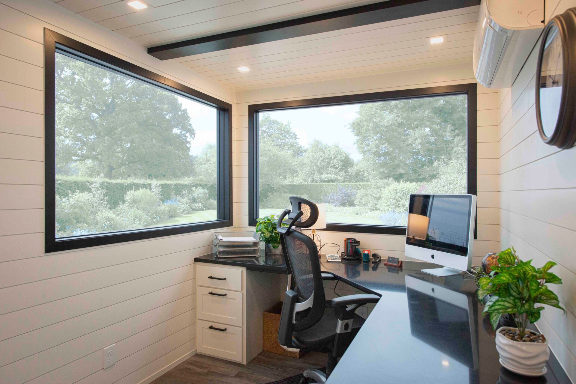 a home office with a desk , chair , computer and large windows