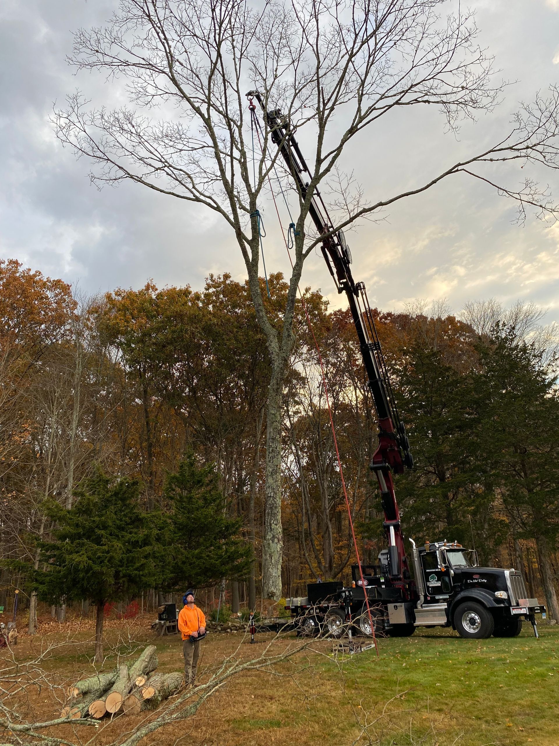 A man is standing next to a truck with a crane attached to it.