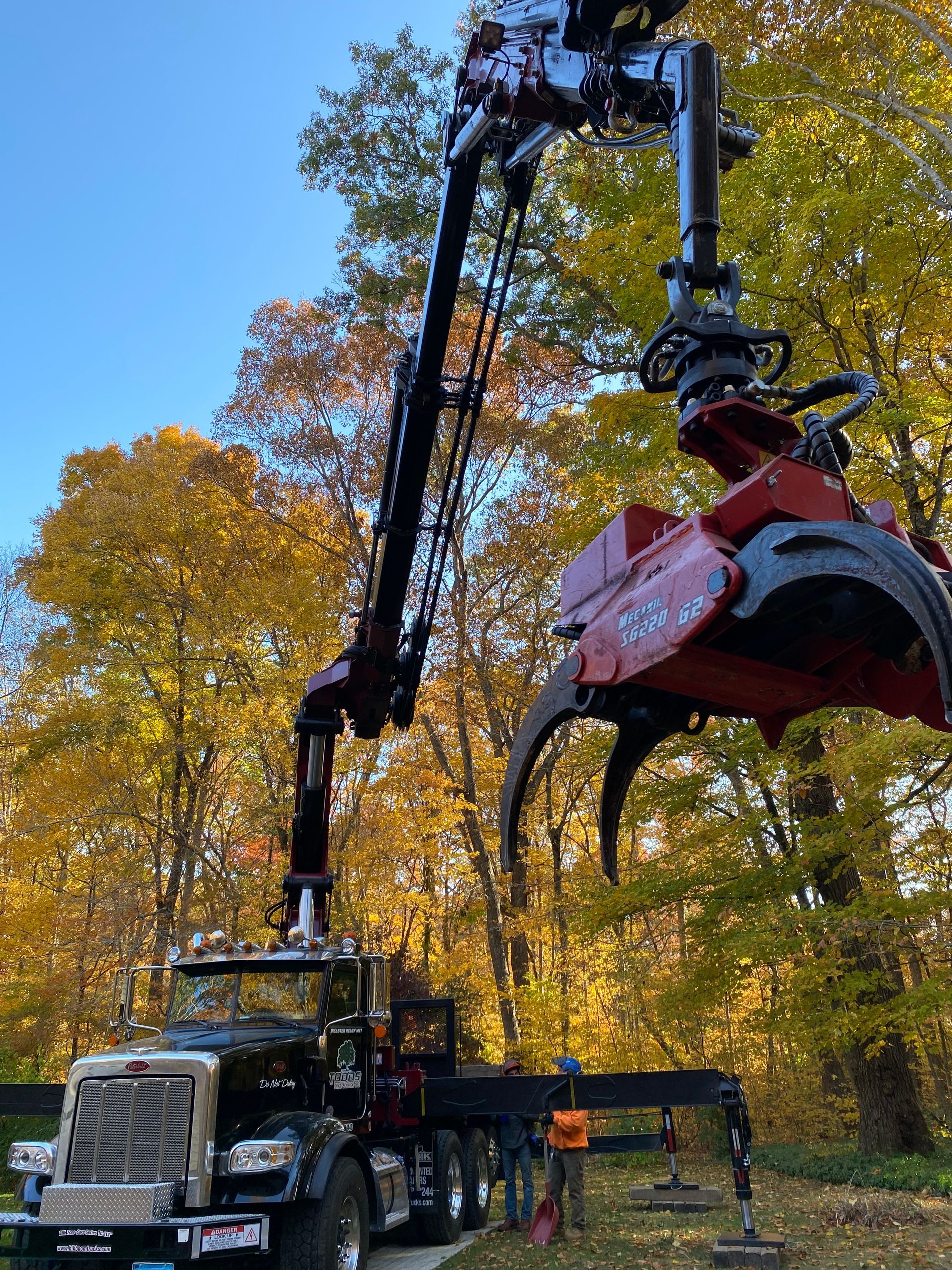 A truck is being lifted by a crane in the woods.