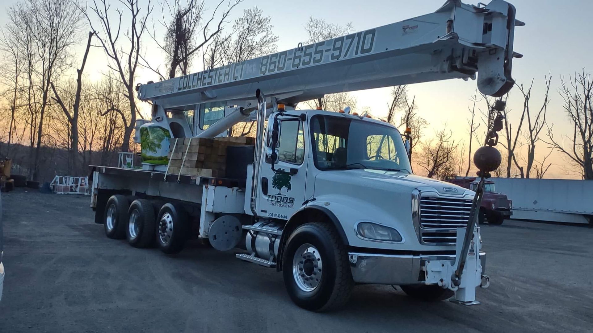 A large white truck with a crane on the back is parked in a parking lot.