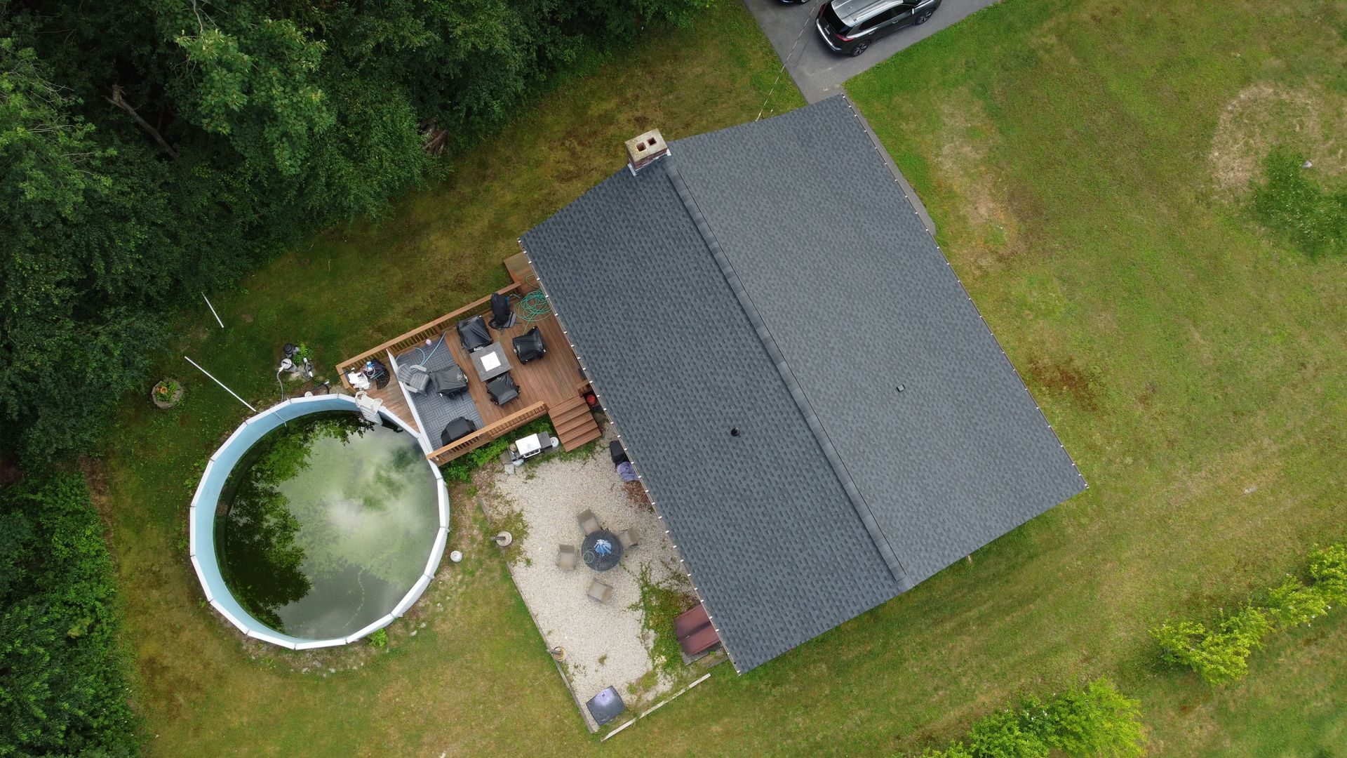 Aerial view of a house with a large circular pool and patio in a grassy yard