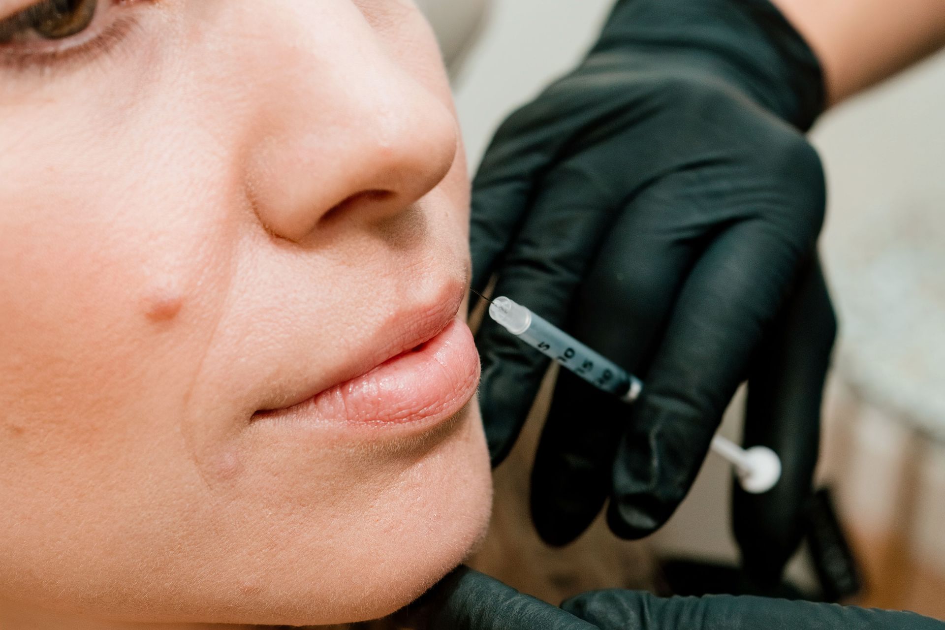 Smiling older woman with gray hair, touching her cheek.