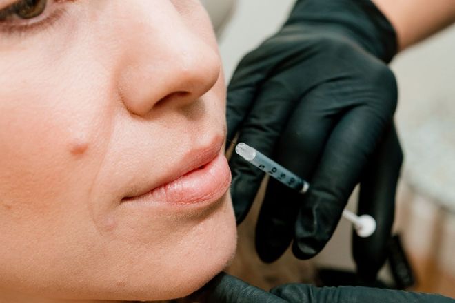 Smiling older woman with gray hair, touching her cheek.