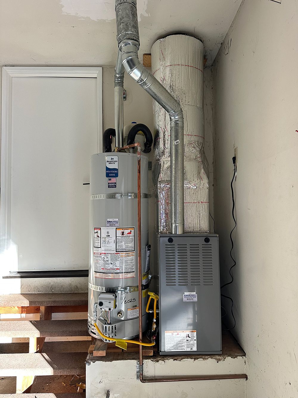 A tall water heater stands next to a gray furnace in a utility room, both vented into a large central chimney.