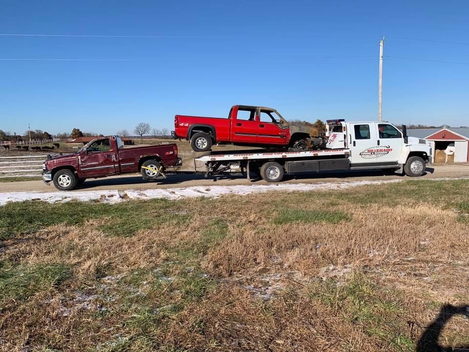 Two trucks are being towed by a tow truck.