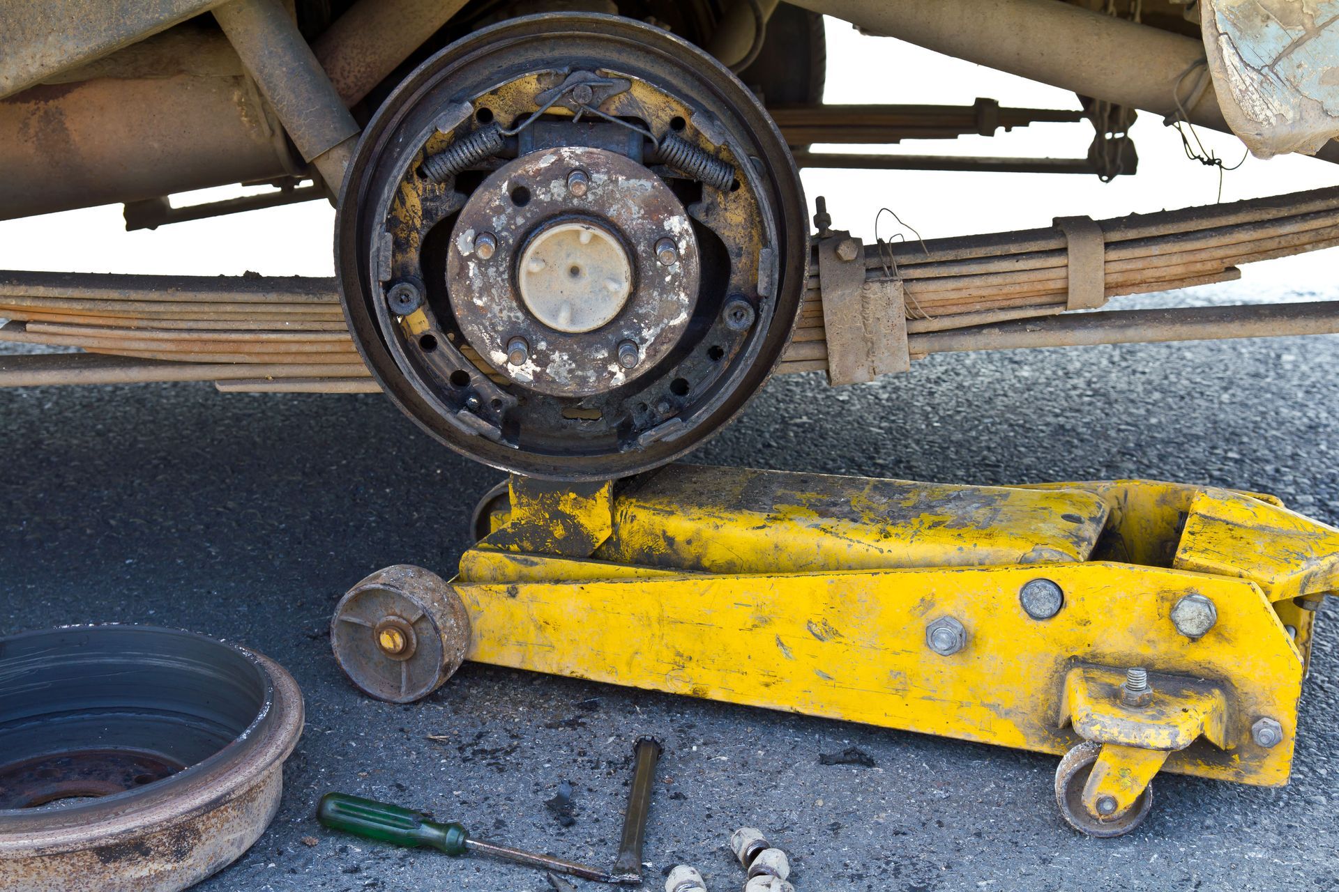 A yellow floor jack is being used to lift a car.