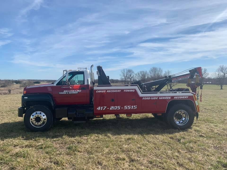 A red tow truck is parked in a grassy field.