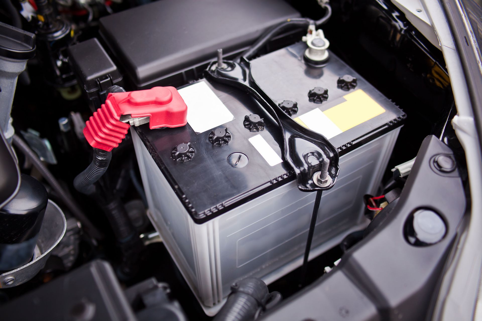 A car battery is sitting under the hood of a car.
