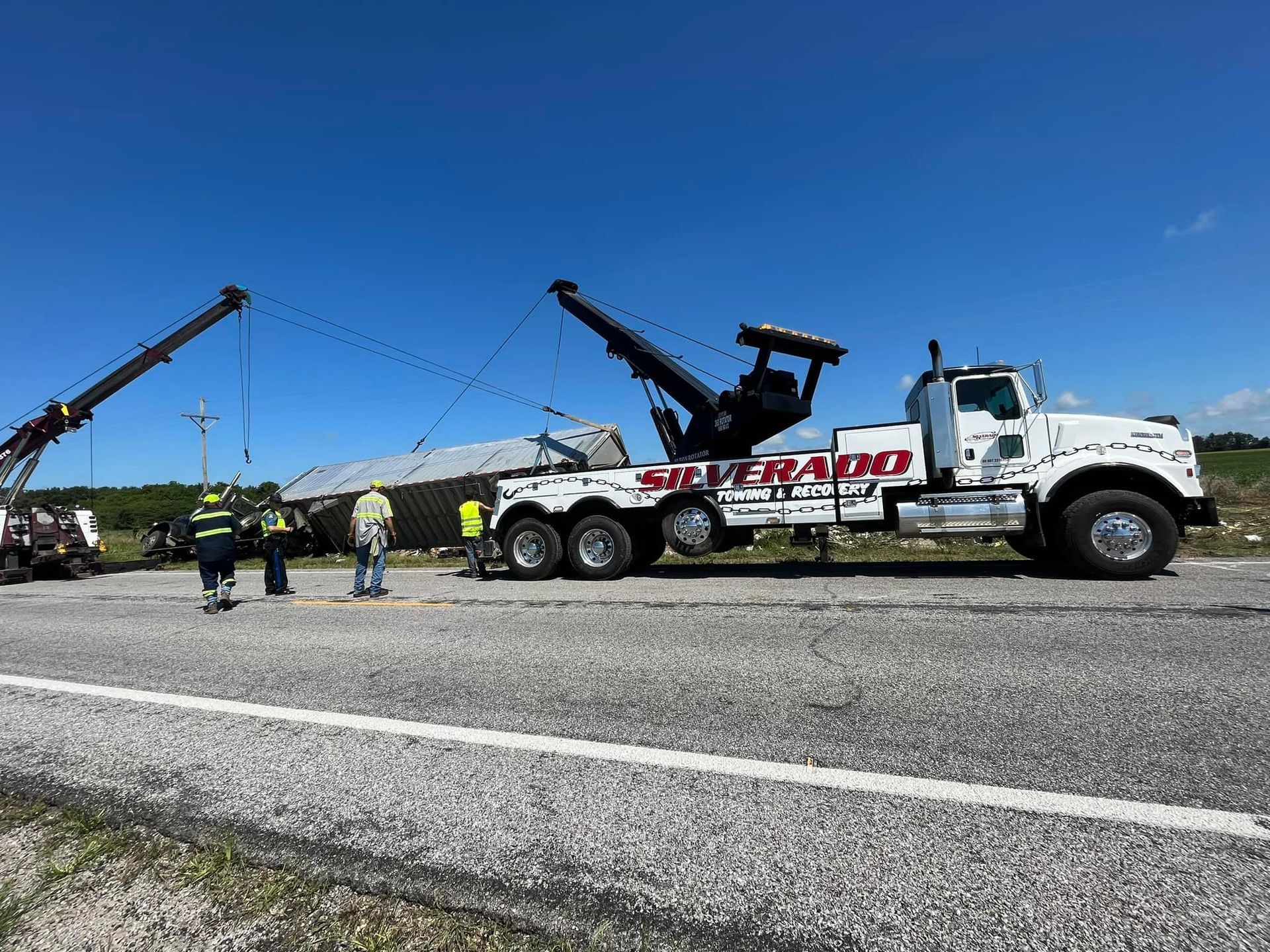 A tow truck is towing a truck on the side of the road.