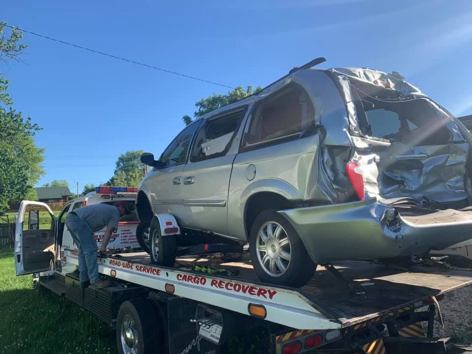 A wrecked car is being towed by a tow truck.