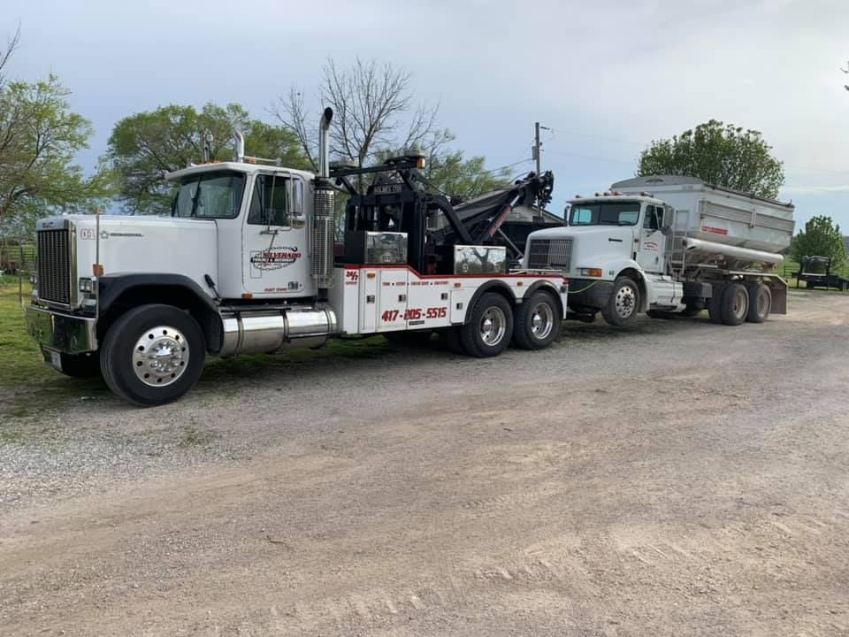 Two tow trucks are parked next to each other in a gravel lot.