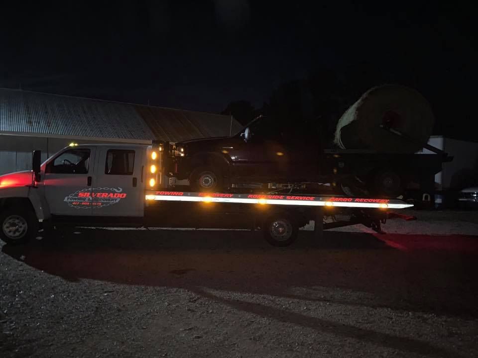 A tow truck is towing a car at night.