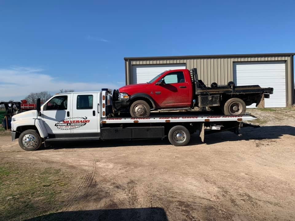 A red truck is being towed by a tow truck.