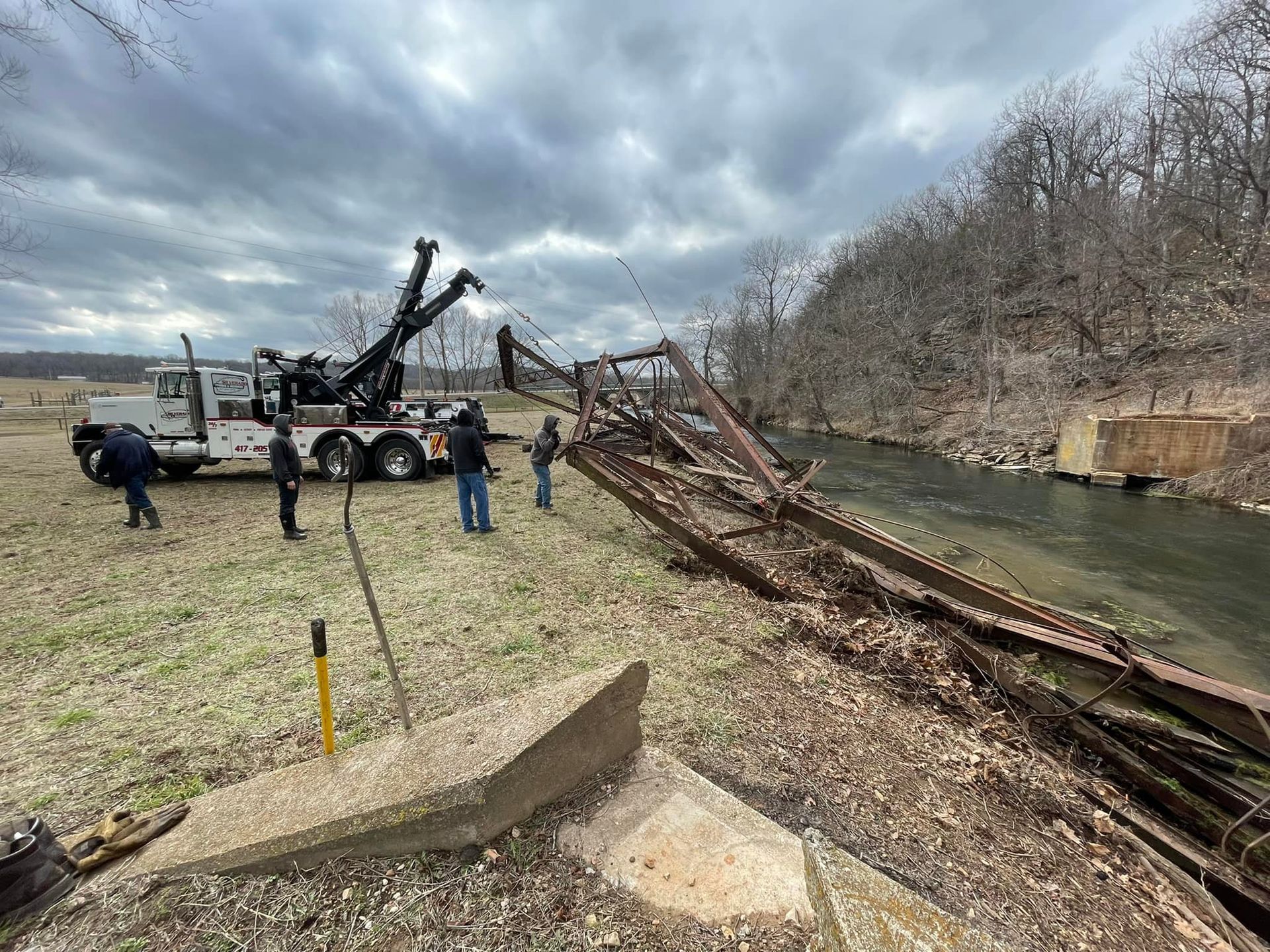 A tow truck is towing a bridge over a river.