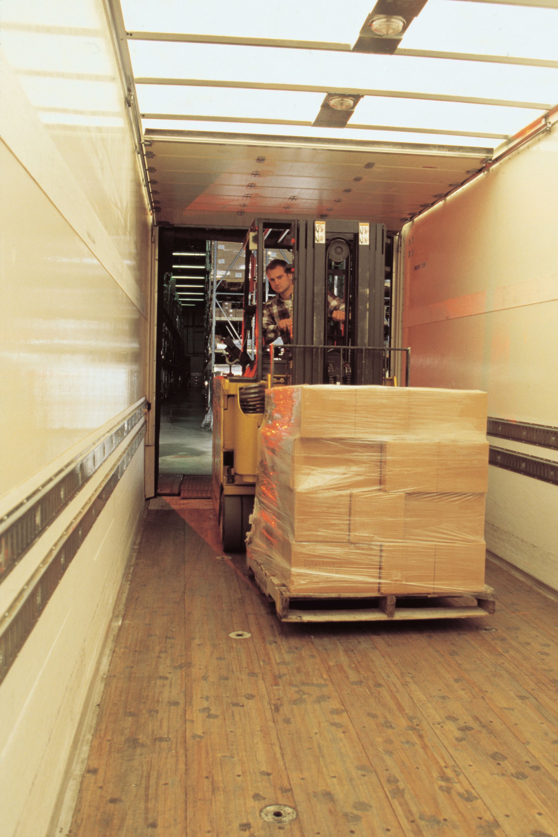 A forklift is loading a pallet of boxes into a truck.