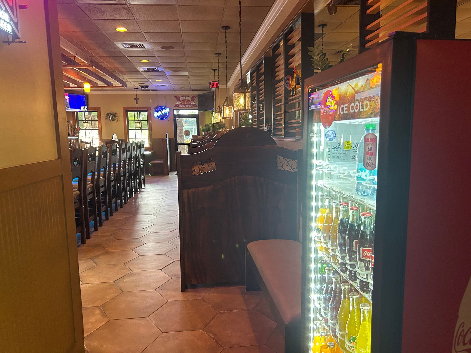 Restaurant interior with soda machine, booths, tables, and a long hallway.