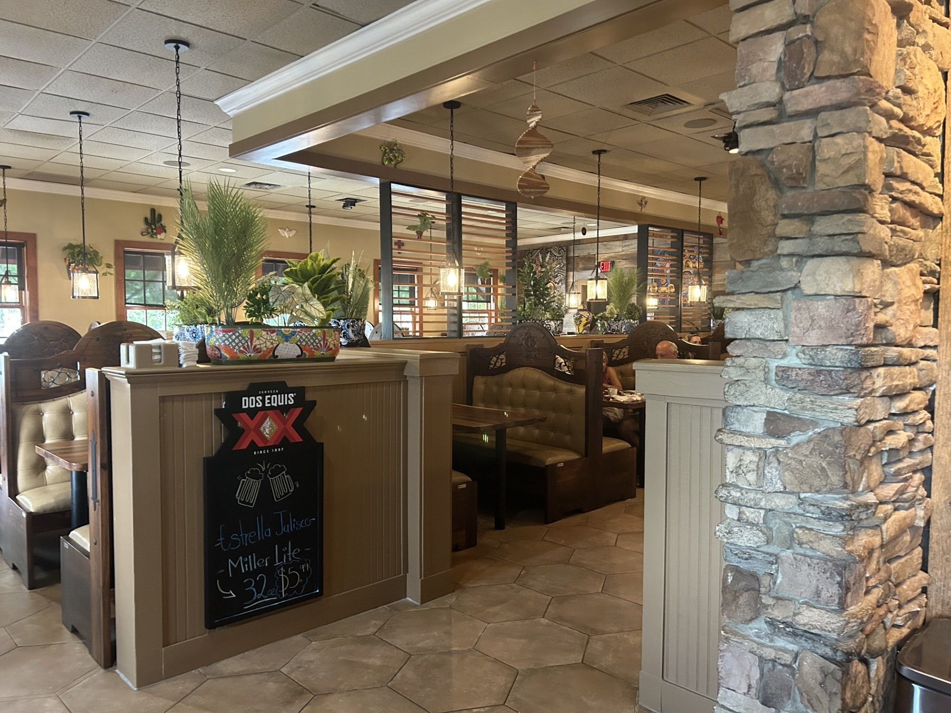Interior of a Mexican restaurant with booths, stone columns, and decorative plants.