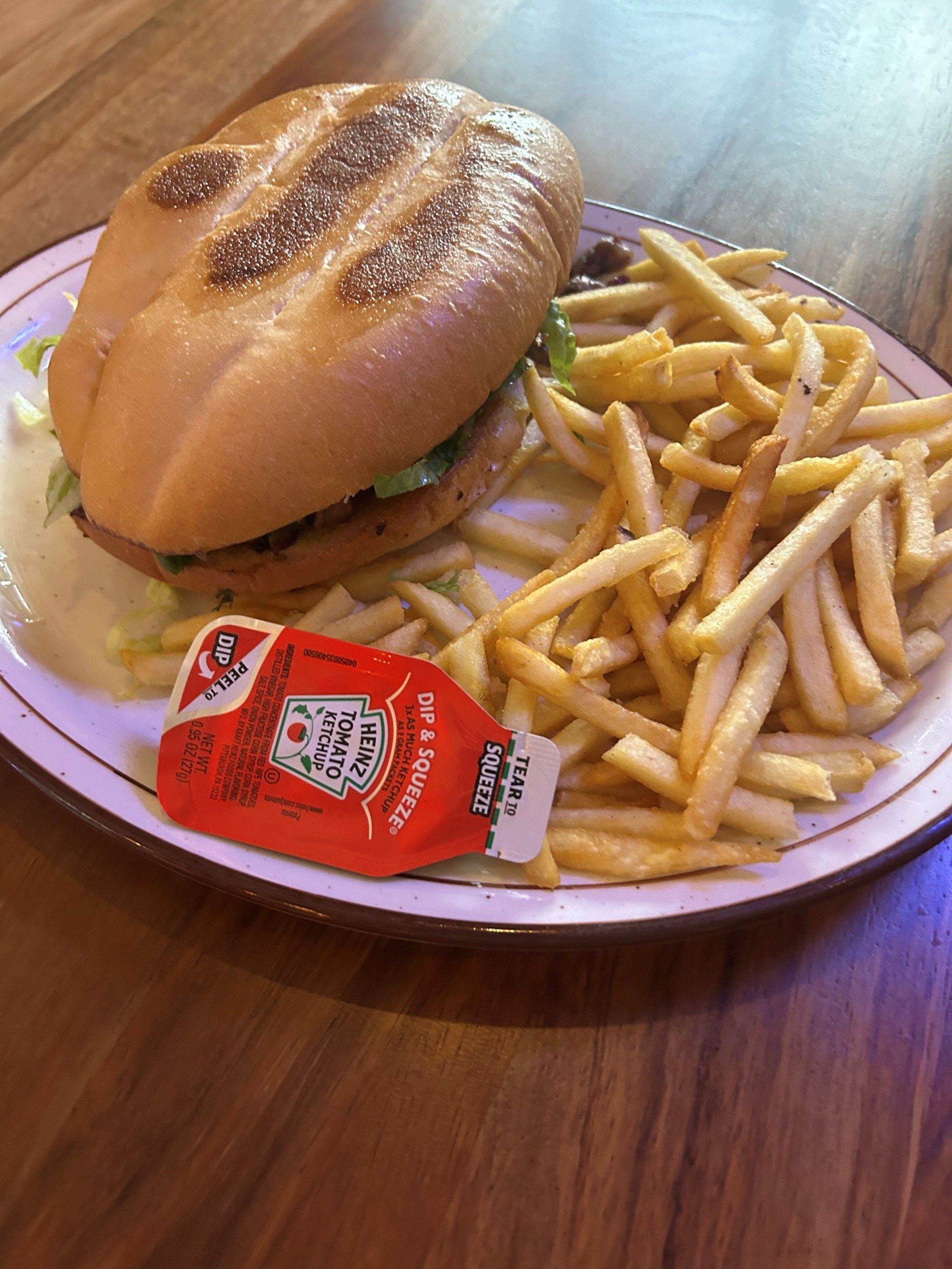 Burger with fries and ketchup packet on a plate.