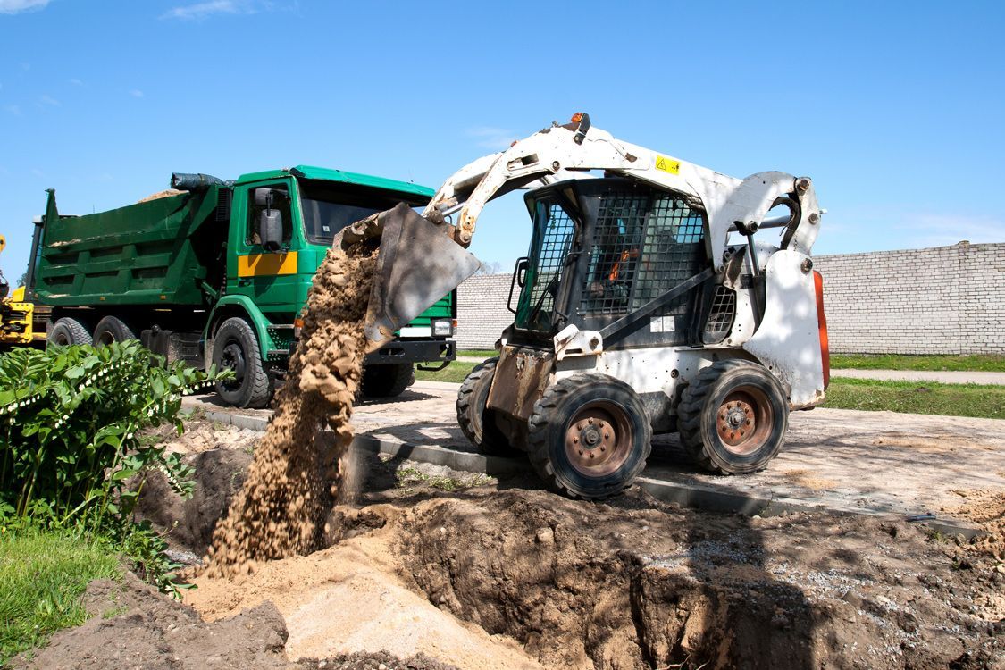 A bulldozer is digging a hole in the ground next to a dump truck.