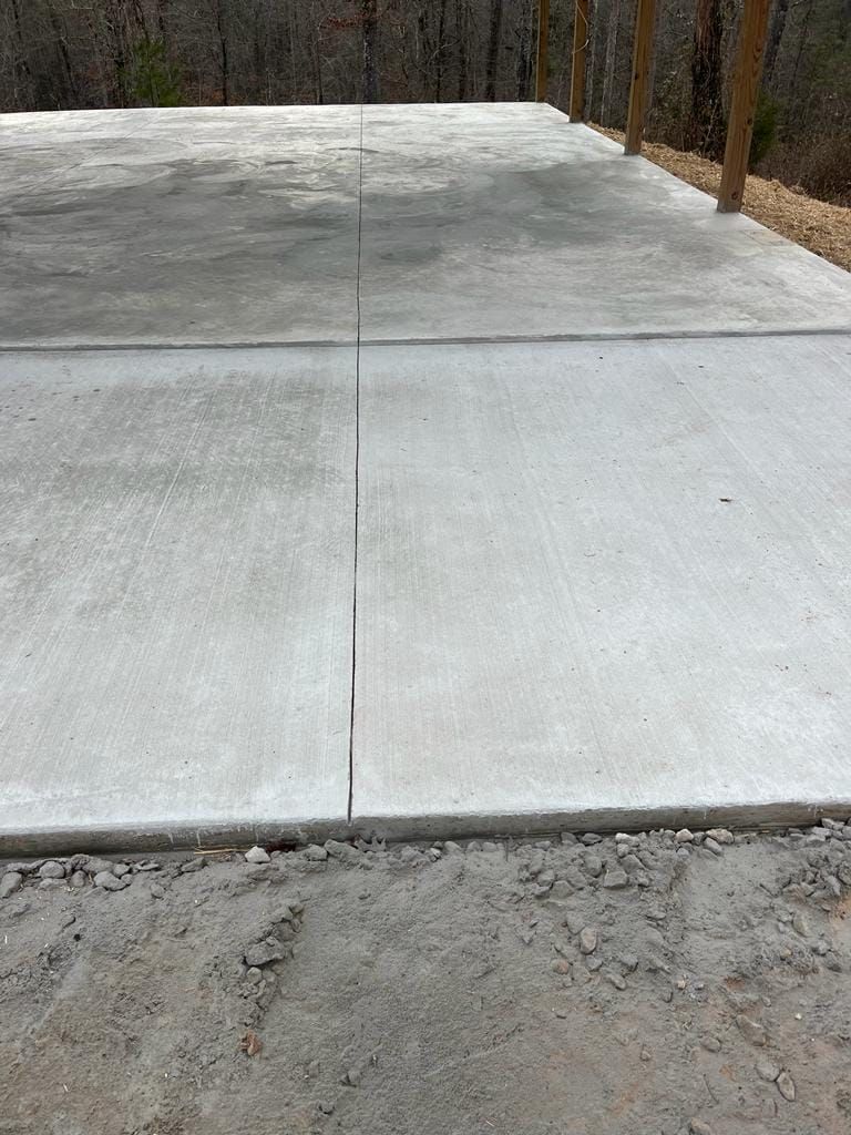 A concrete driveway with a wooden fence in the background.