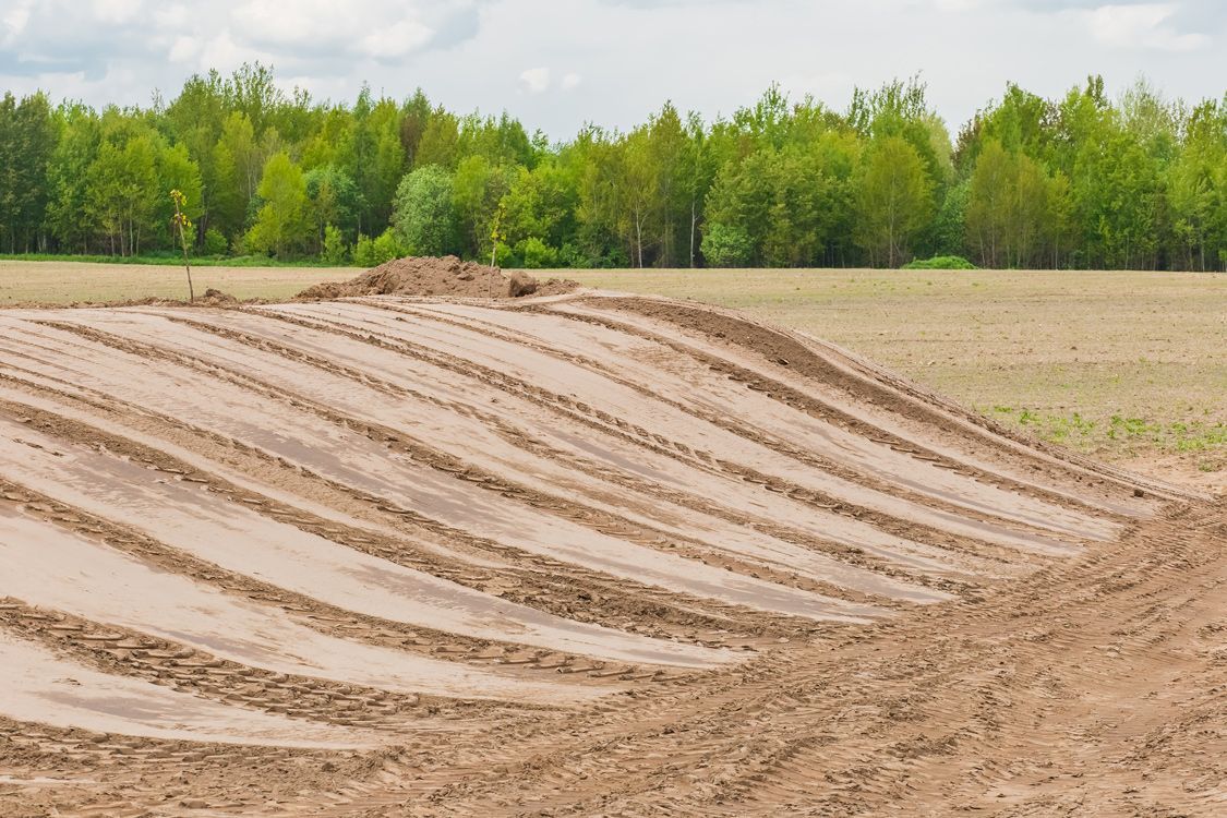 There are many tire tracks in the dirt in the middle of a field.