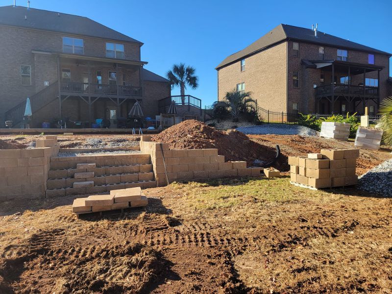 A brick wall is being built in the backyard of a house.