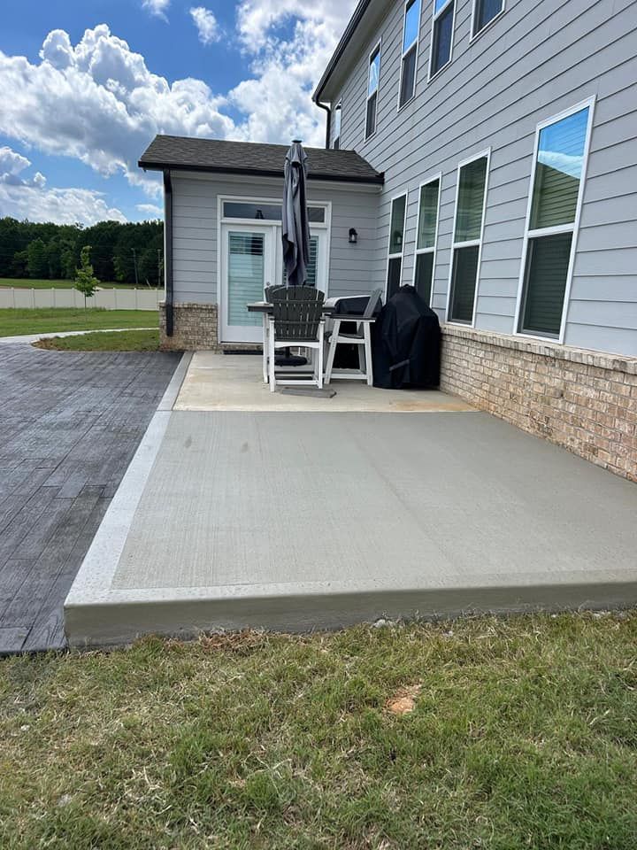 A patio with a table and chairs, and an umbrella in front of a house.