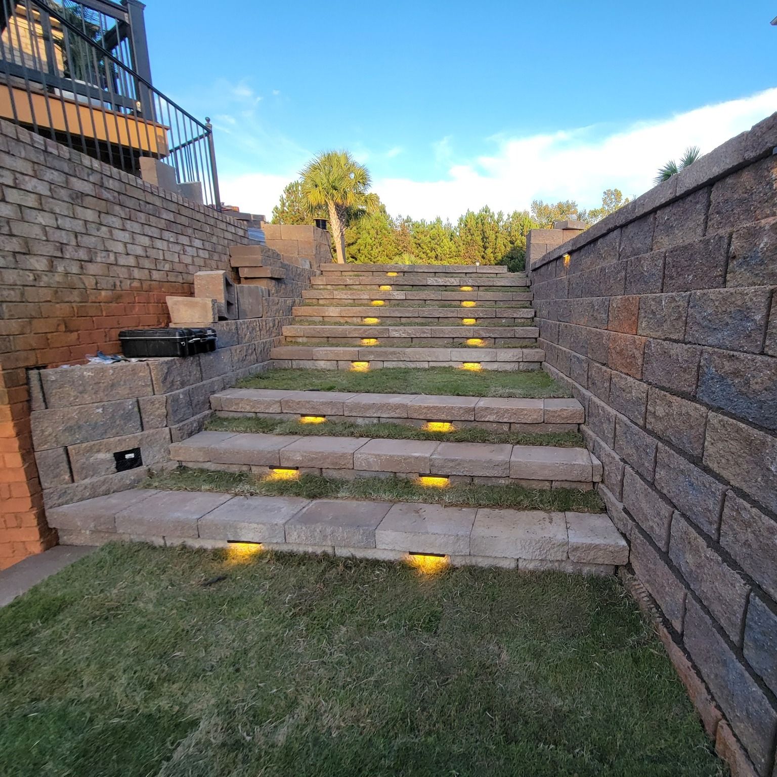 A set of stairs leading up to a brick wall with lights on them.