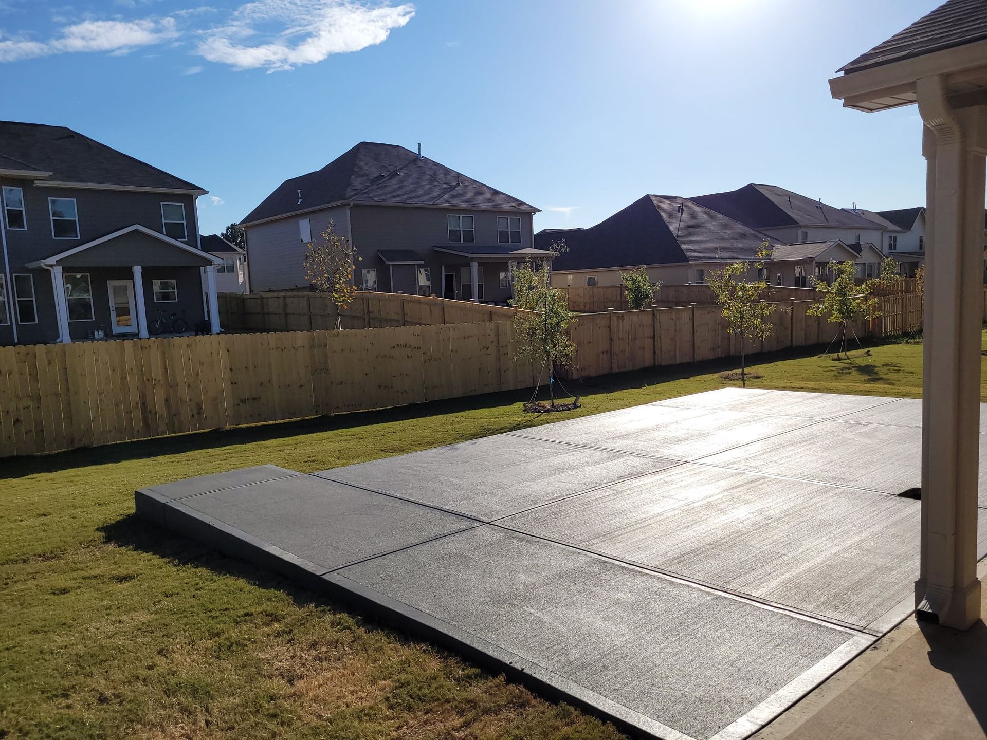 A backyard with a concrete floor and a wooden fence.