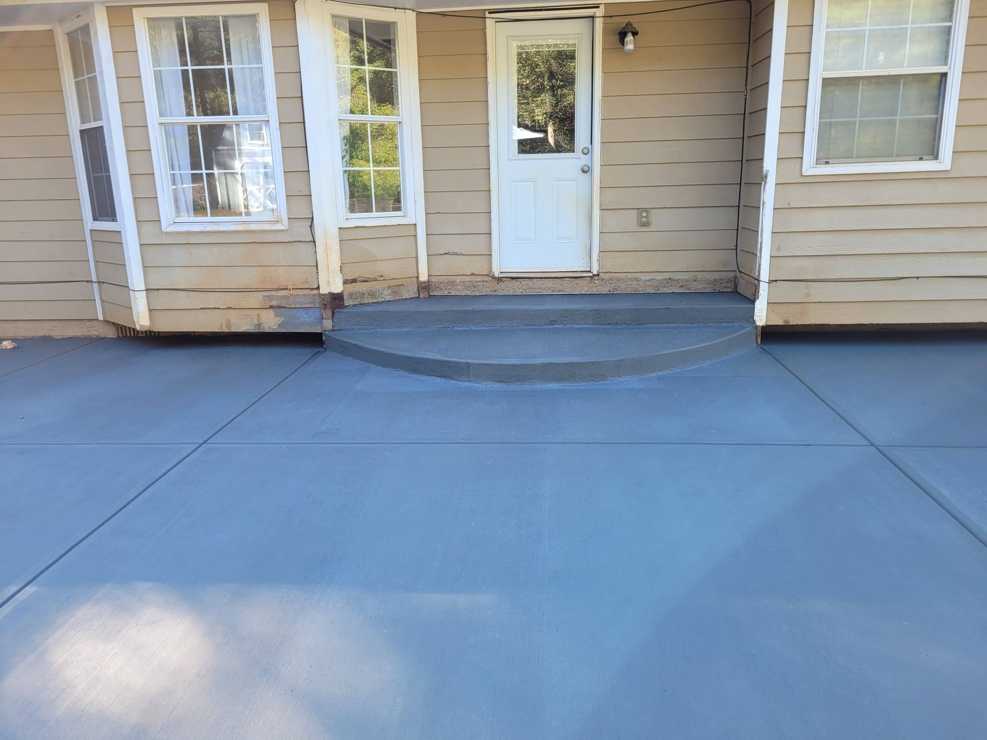 A concrete driveway with steps leading to the front door of a house.