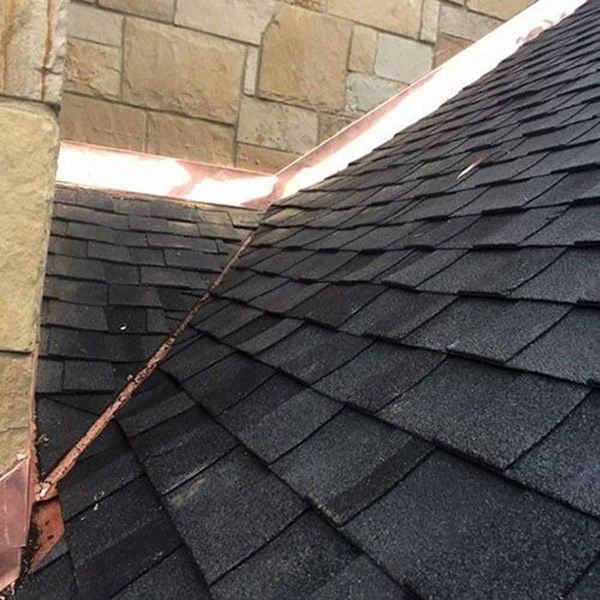 A close up of a roof with black shingles