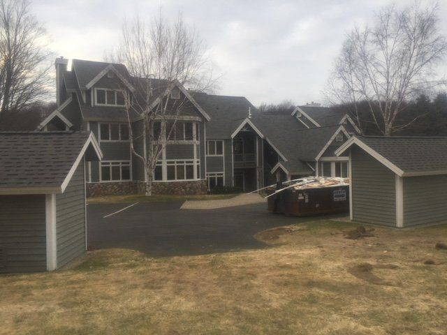 A large house with a dump trailer parked in front of it