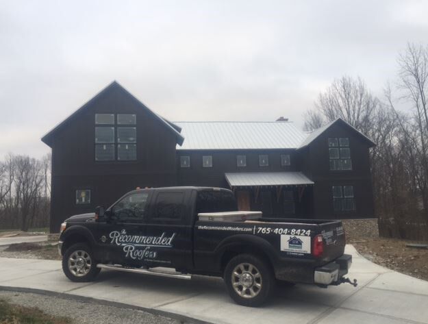 A black truck is parked in front of a large house