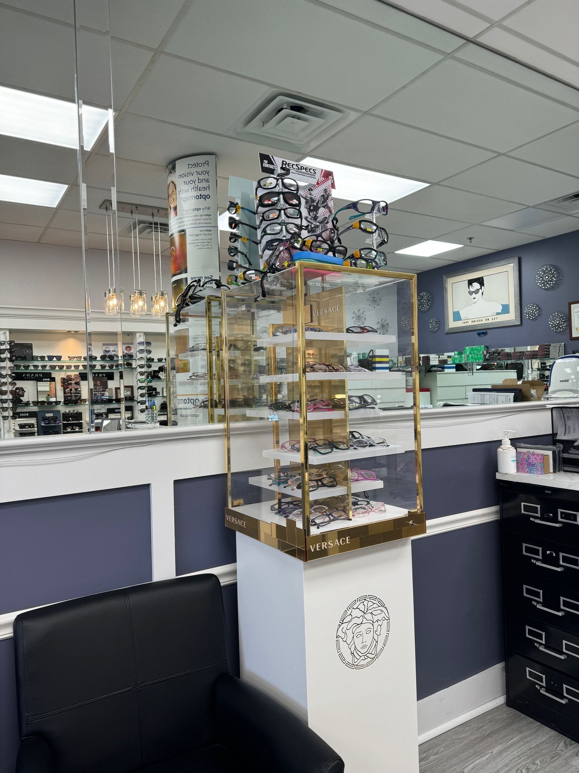A waiting room with a chair and a display case of glasses