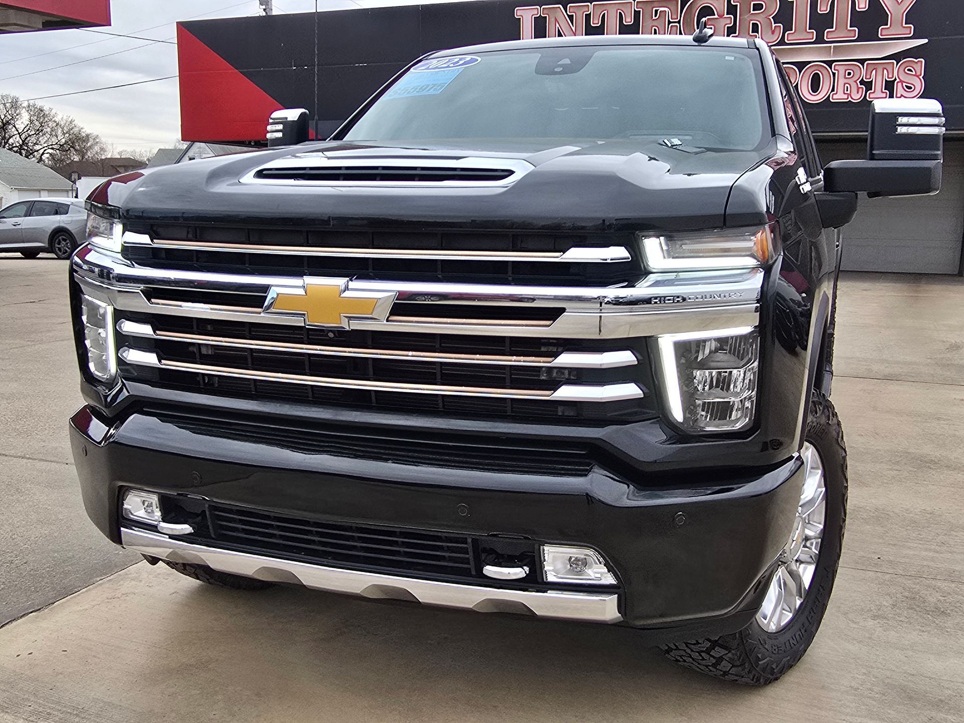 Black Chevrolet Silverado truck in front of a dealership with chrome accents and bright headlights.
