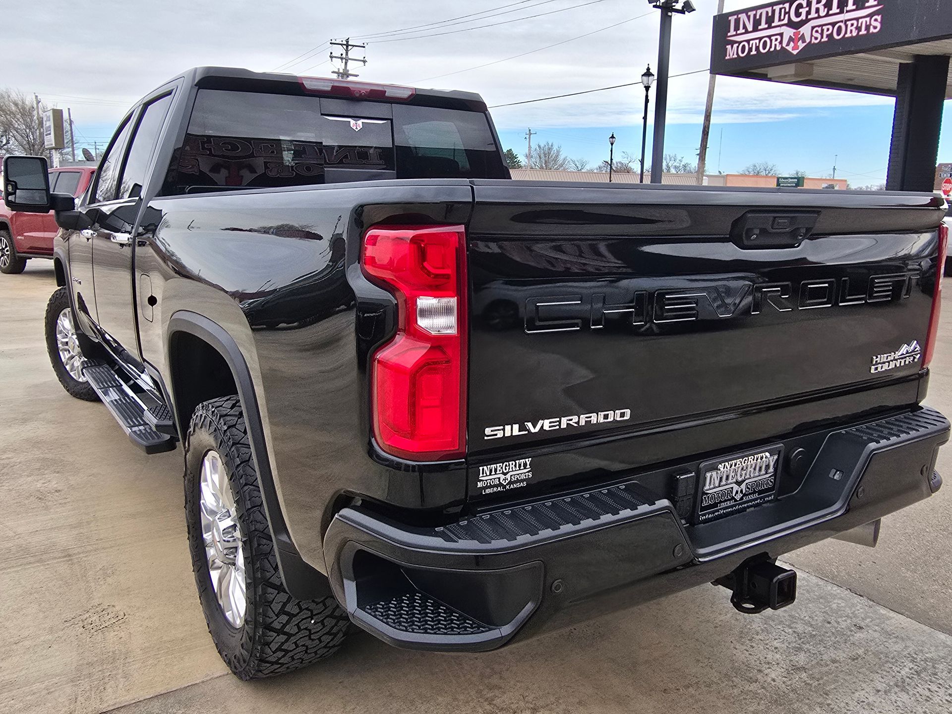 Black Chevrolet Silverado truck, rear view, parked outdoors at a dealership with the name