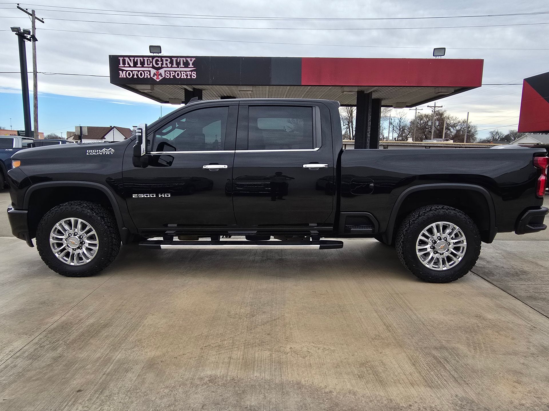 Black pickup truck parked in front of a building with a red and black awning.