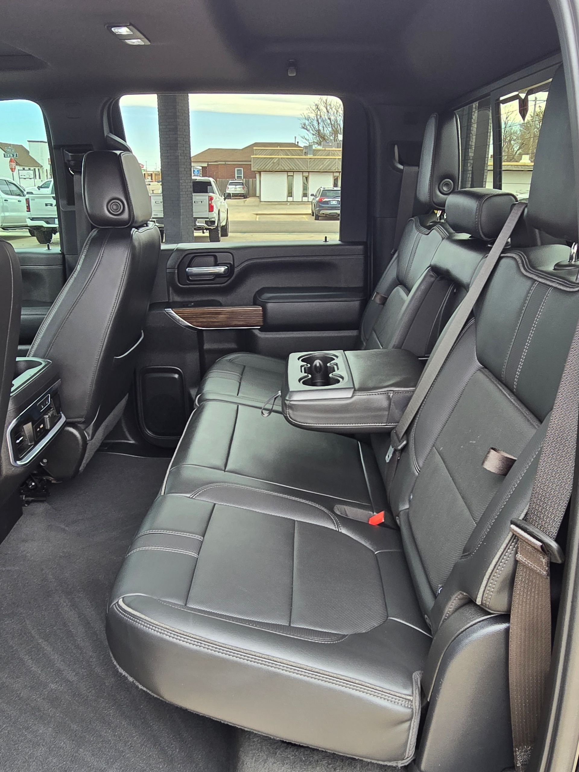 Black leather truck backseat with a fold-down center armrest and cupholders.