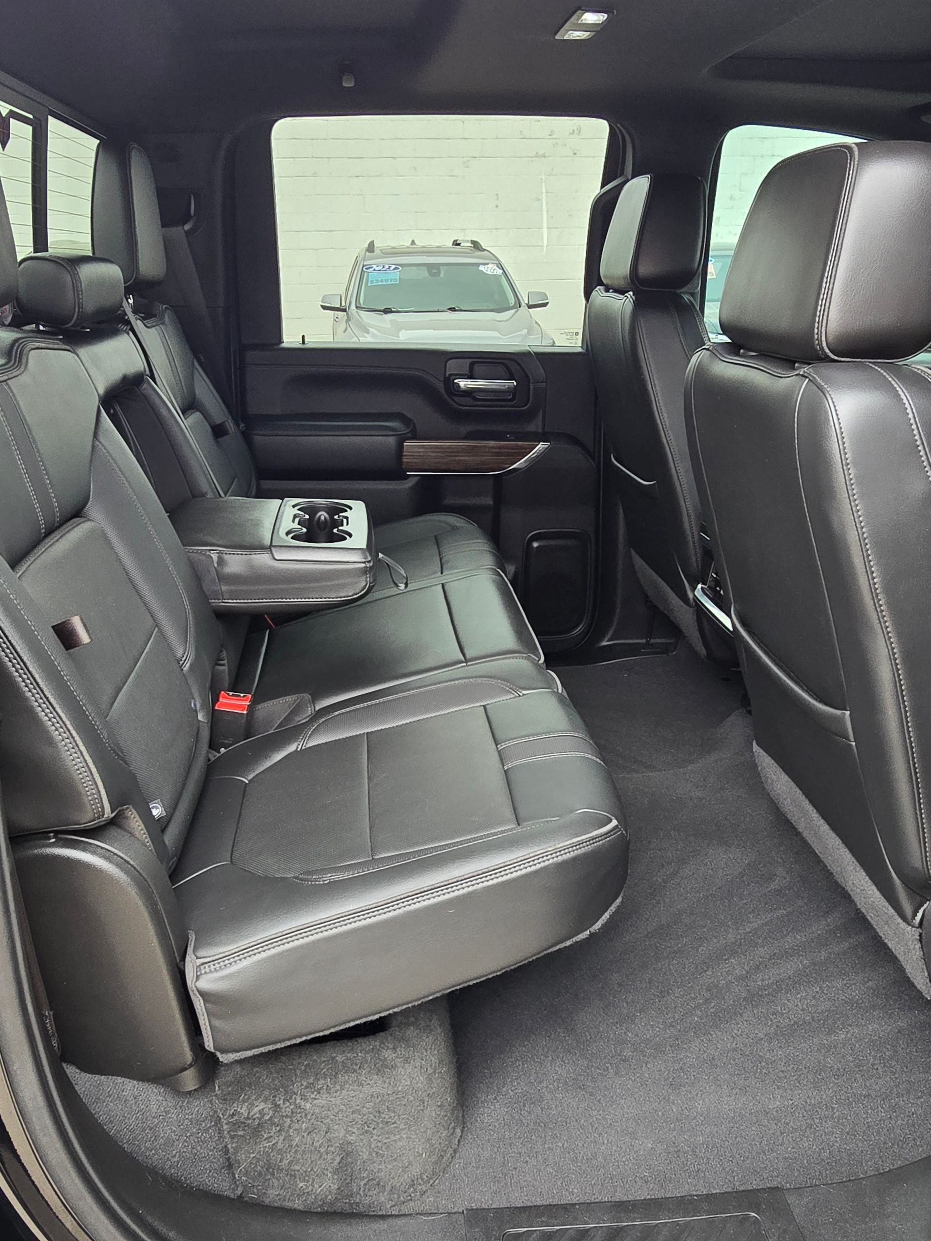 Black leather interior of a truck's back seat, featuring a center armrest with cupholders.