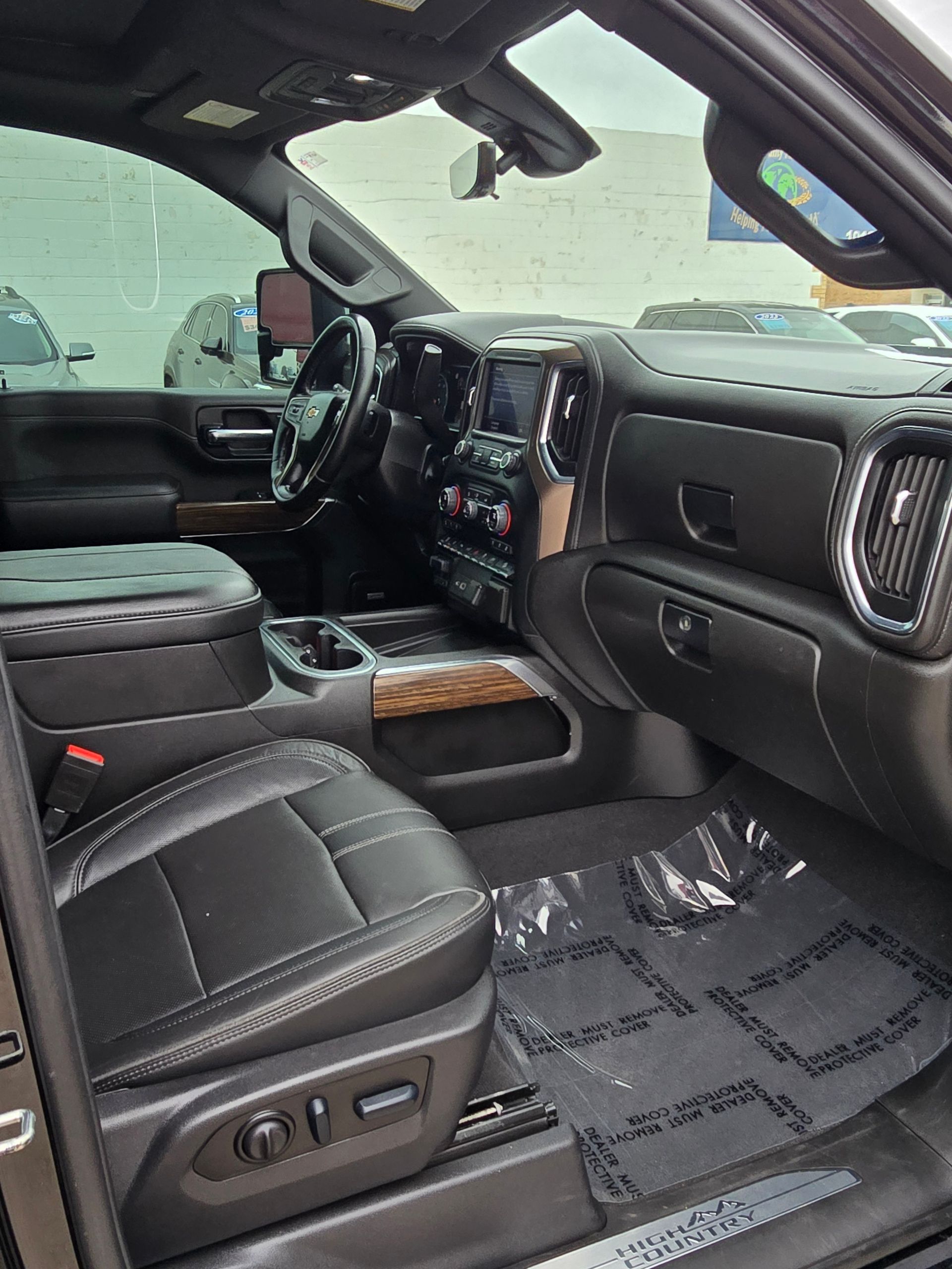 Interior of a black truck with black leather seats, a wood-grain dashboard, and protective floor mats.