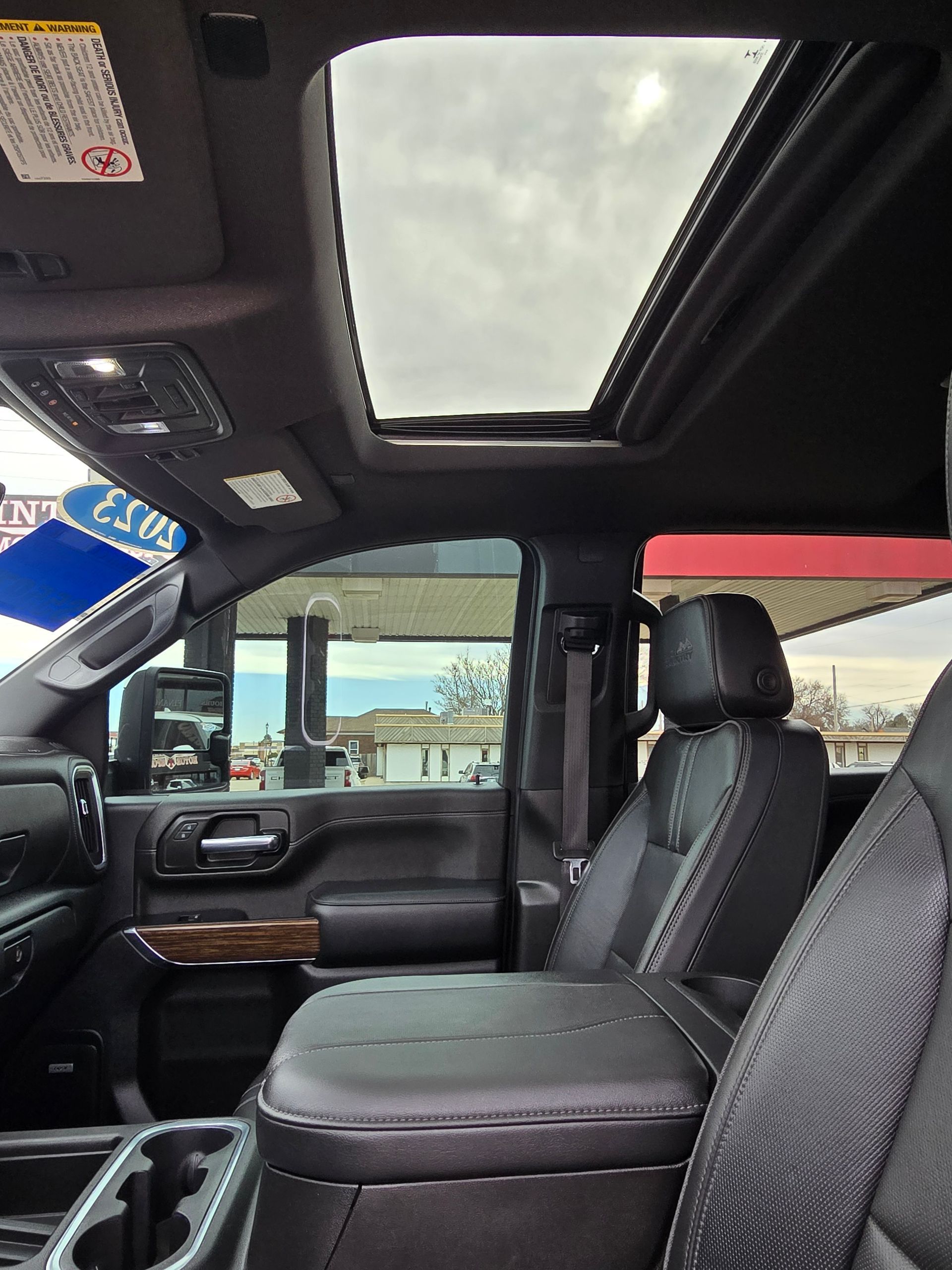 Interior view of a black pickup truck with an open sunroof. Black leather seats and a console are visible.