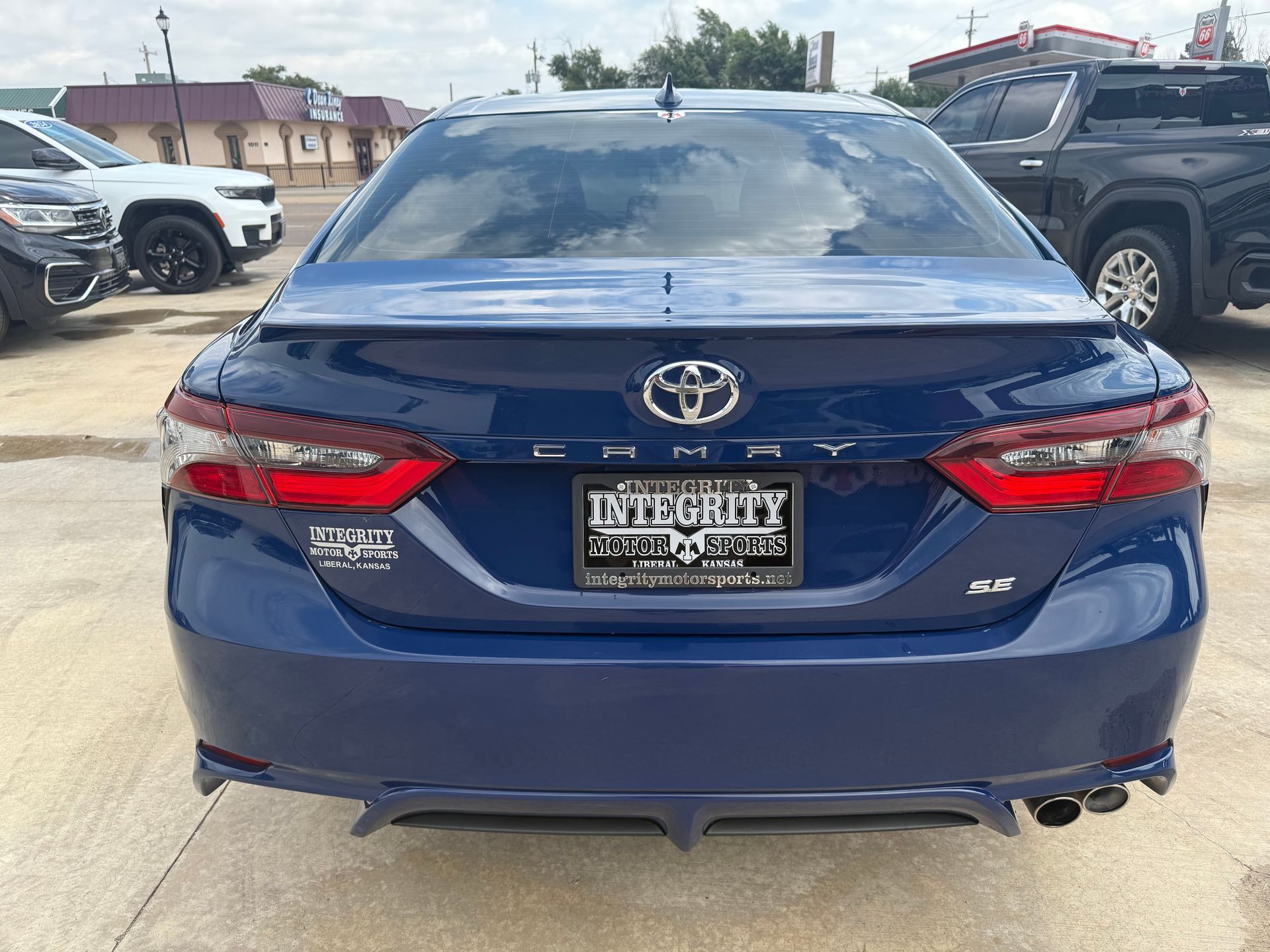 Blue Toyota Camry sedan parked outside a car dealership.
