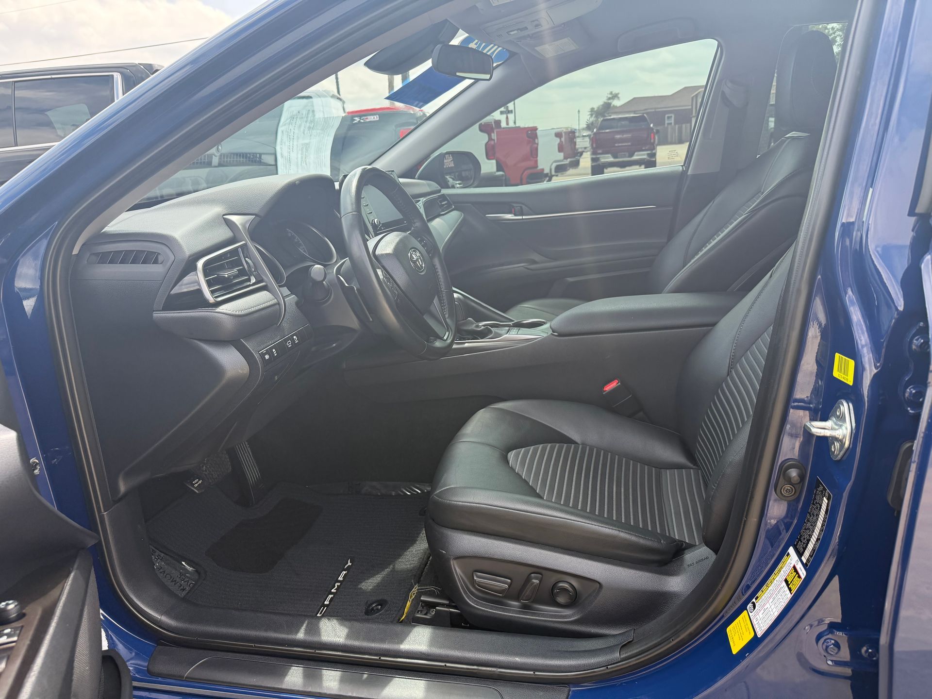 Interior of a blue car with black leather seats, a steering wheel, and a visible dashboard.