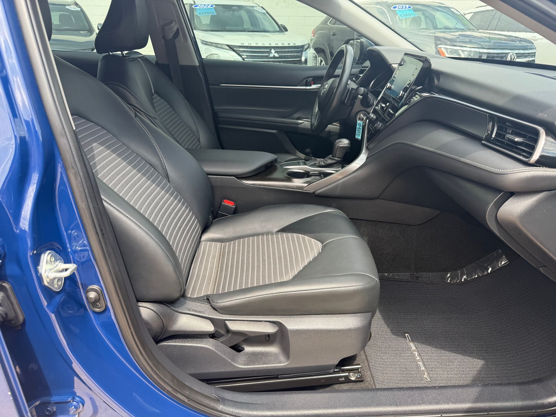 Blue car interior: black seats, dashboard, steering wheel, and window.